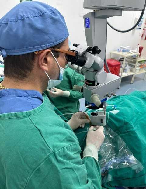 El oftalmólogo y retinólogo Javier Andrés Bernal Urrego utilizando un microscopio en un quirófano, realizando correcciones visuales.