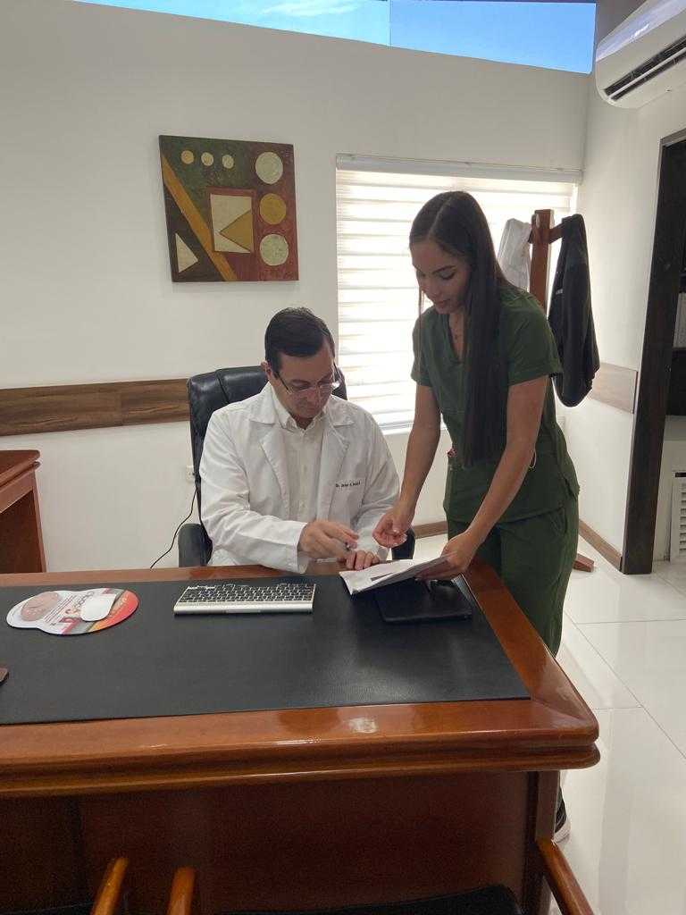 Un médico oftalmólogo y su asistente revisan los documentos y examenes de los pacientes.