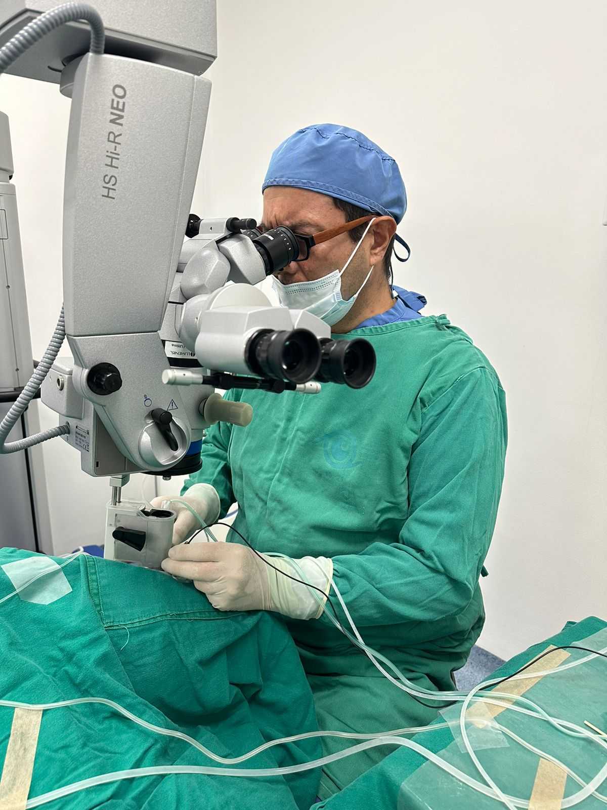 El oftalmólogo y retinólogo Javier Andrés Bernal Urrego está utilizando un microscopio para realizar una cirugía en el ojo de un paciente para realizar correcciones visuales.